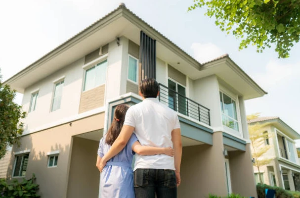 Un couple admirant leur maison neuve de l'extérieur.